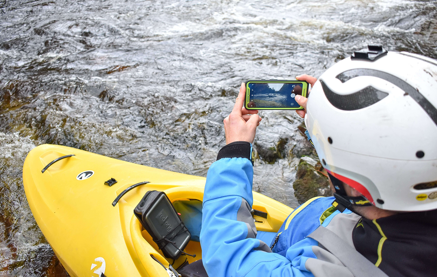 A Man Sat In His Kayak Taking A Photo With His Phone