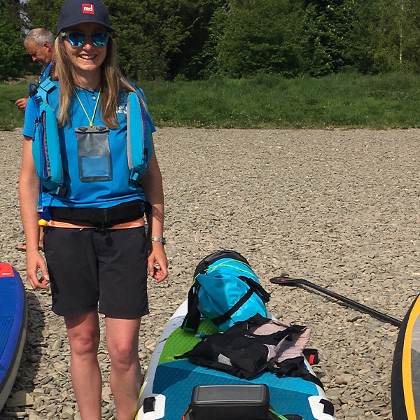 Lucy standing by her loaded paddle board.