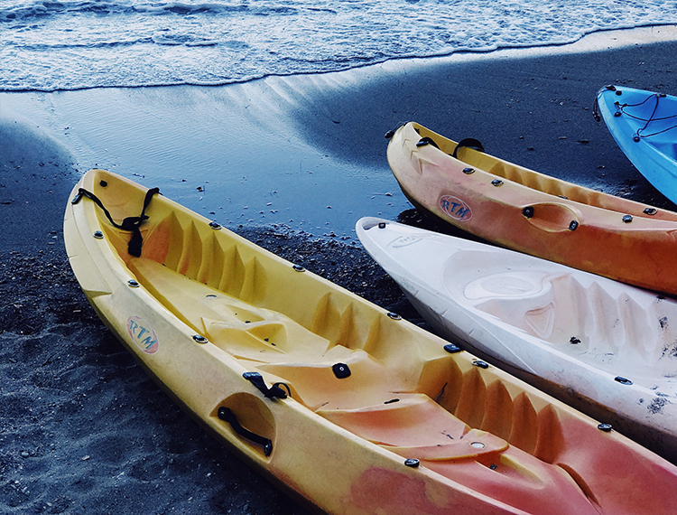 Sea Kayaks Sat On The Beach Next To The Sea