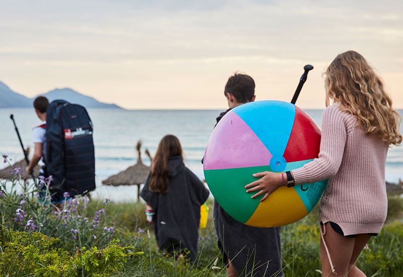 family with beach ball walking to the beach