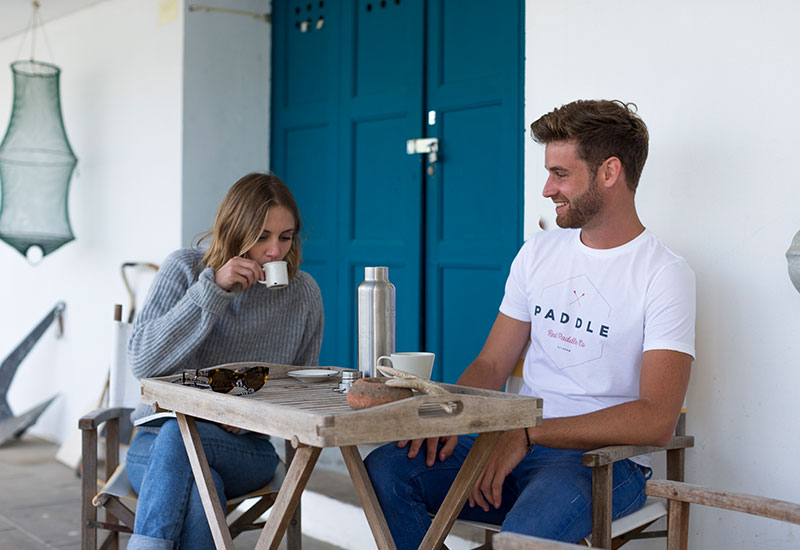 couple enjoying a coffee wearing Red Original Paddle On white t-shirt