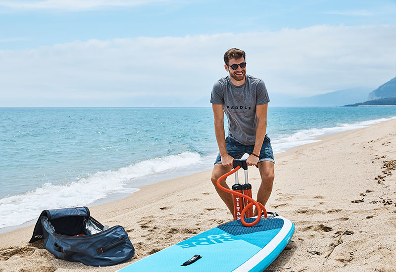 Man umping up a sup wearing a Red Original Paddle On grey t-shirt