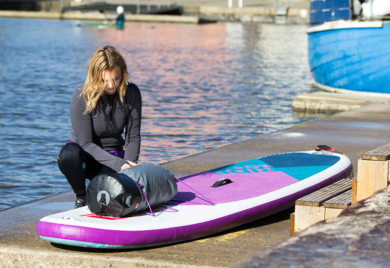 Attaching a Red Original Roll Top Dry Bag to a paddle board