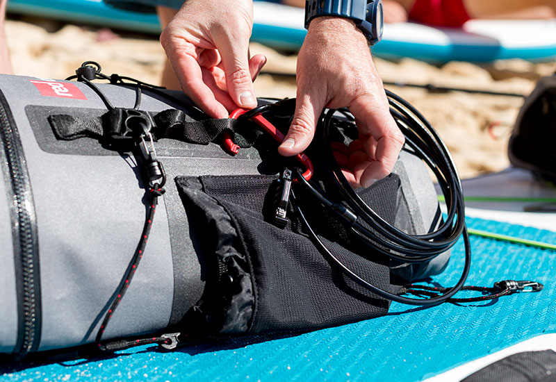attaching a Red Original board lock onto the side of a deck bag on a sup