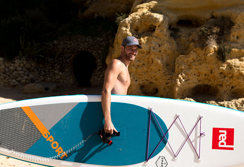 carrying an sup to the water wearing the Red Original Paddle Cap