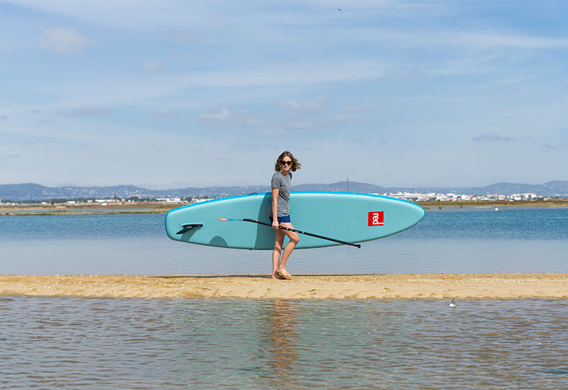 female carrying a SUP whilst wearing the Red Original Women's Performance T Shirt