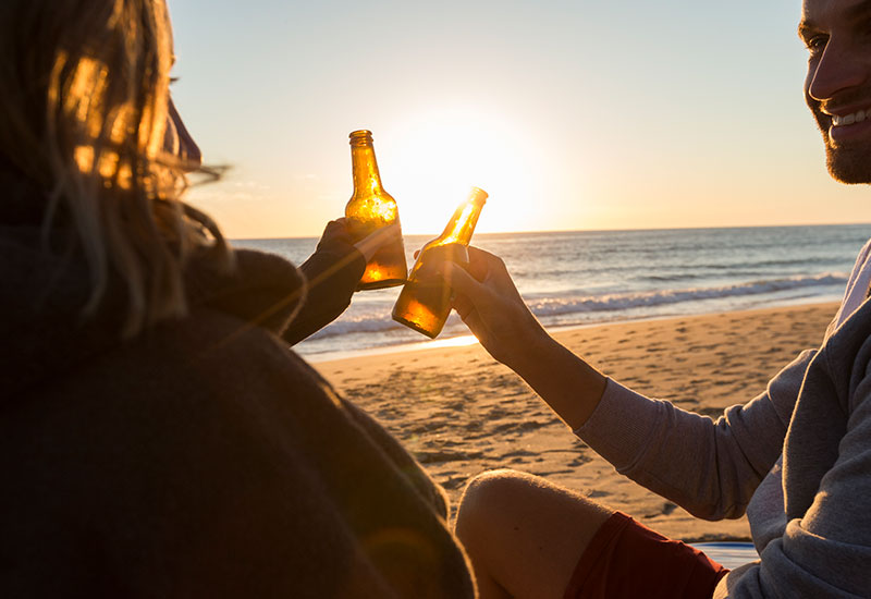 people enjoying beers at sunset on beach