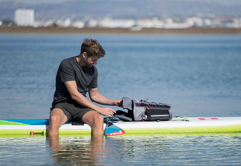 man accessing the contents of the Red Original deck bag whilst on the water