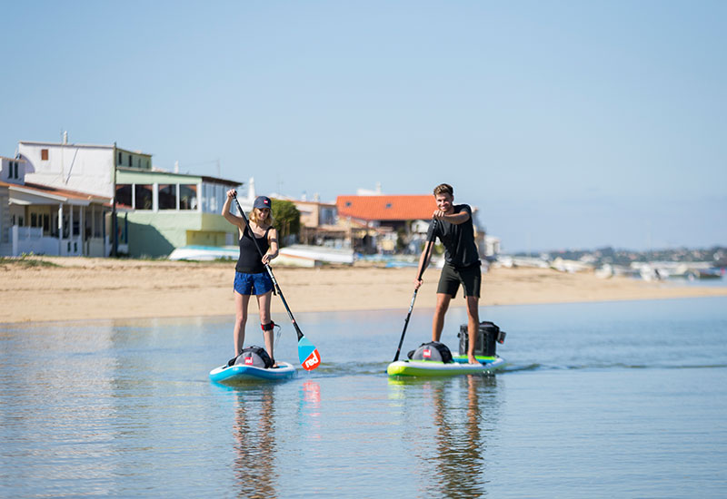 couple paddle boarding with deck bags
