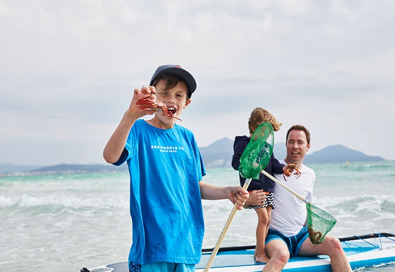 family with fishing nets at beach and child holding crab