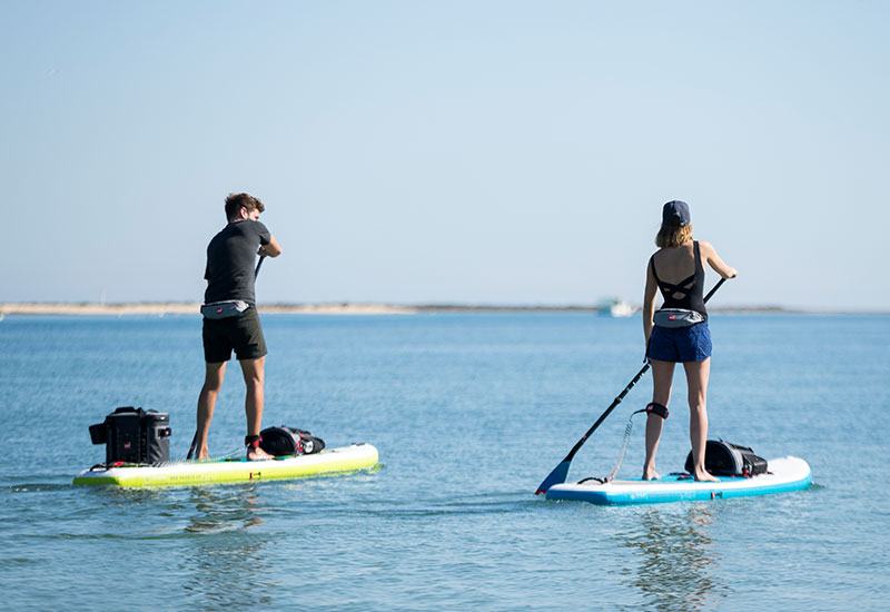Couple paddle boarding wearing Red Original Airbelt PFDs