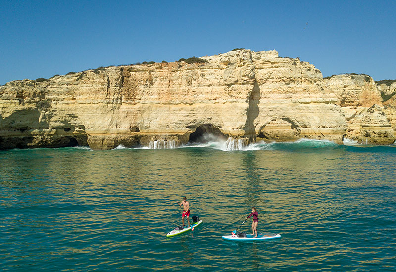 couple out on a paddle boarding adventure with Red Original deck bags on their sups