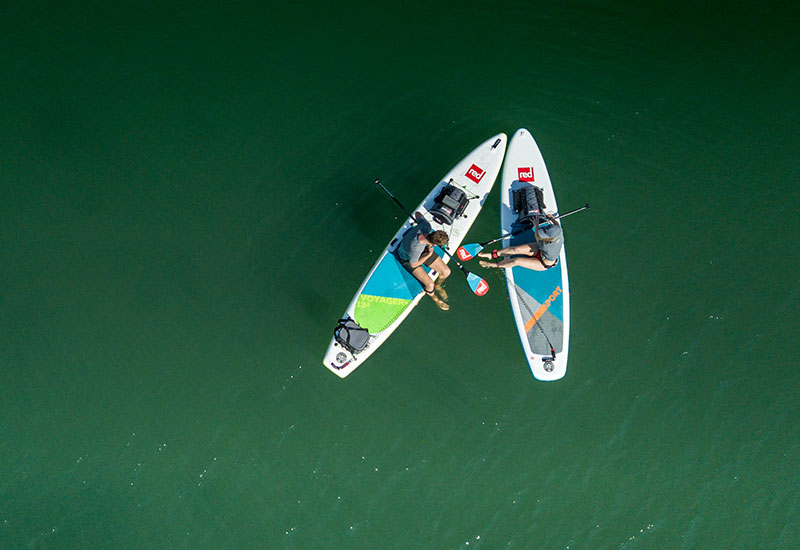 Couple resting on the water whilst wearing Red Original Performance T Shirts